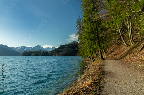 autumn clear weather day time forest mountain landscape with dirt trail for peaceful walking along pond