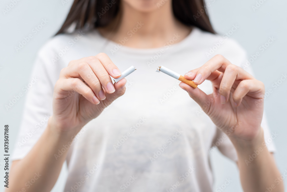 Stop smoking and Quit smoking cigarettes concept. Portrait of beautiful girl holding broken cigarette in hands. Happy female quitting smoking cigarettes. Quit bad habit, health care concept. Stop smoking and Quit smoking cigarettes concept. Portrait of beautiful girl holding broken cigarette in hands. Happy female quitting smoking cigarettes. Quit bad habit, health care concept.