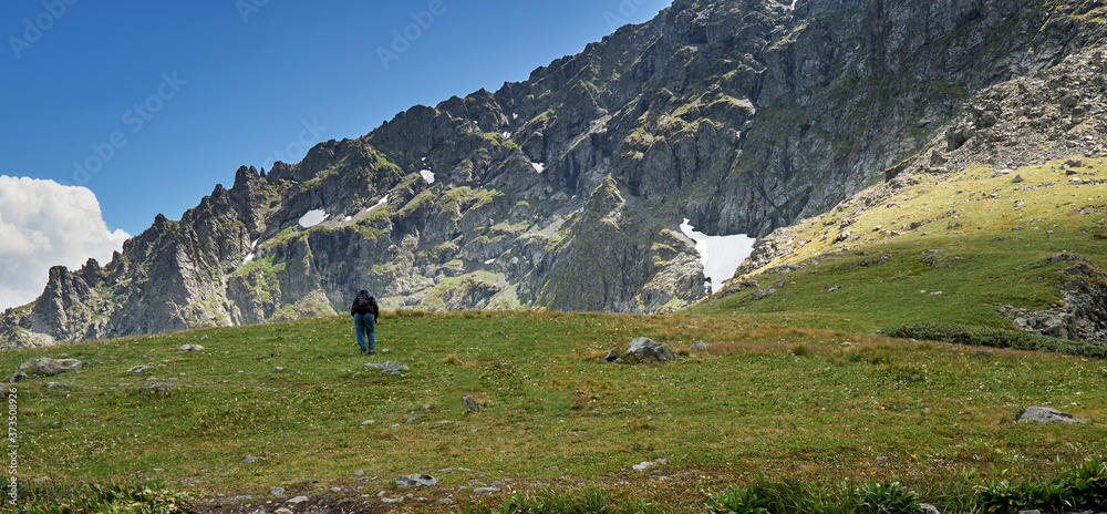 male tourist with a backpack climbs to the top of the mountain