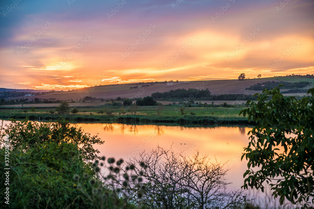 Obraz premium Sonnenuntergang über ländlicher Region mit Spiegelungen im See