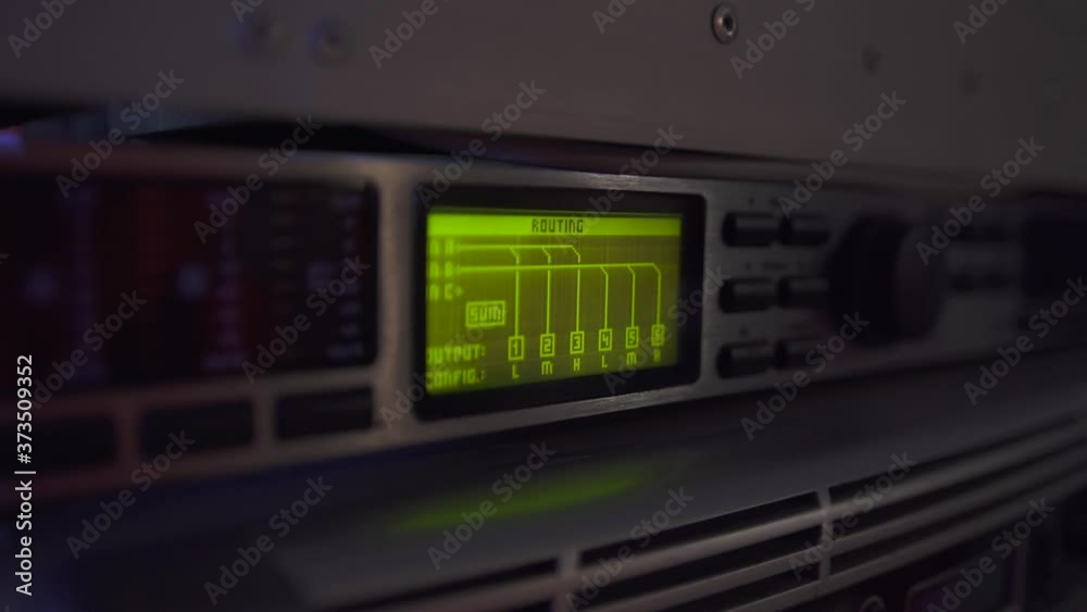 Close up green light screen of routing on digital sound console of professional audio equipment. Levels on screen, buttons on the panel. Close up green light screen of routing on digital sound console of professional audio equipment. Levels on screen, buttons on the panel.