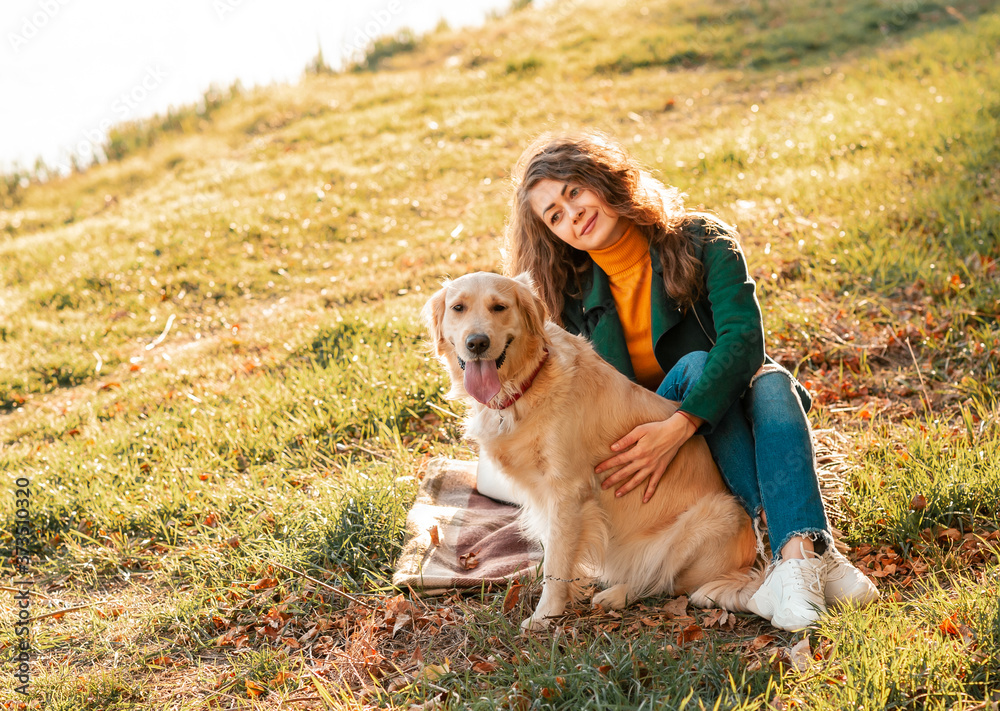 Golden retriever dog with a curly woman walking outdoors on sunny day. Training the dog in the park. love and care for the pet.