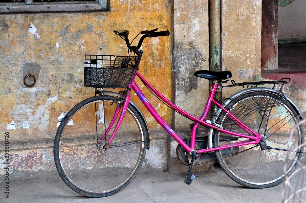 Pink old bicycle in the street.