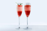 Cooling Rossini italian alcoholic cocktail with sparkling wine, strawberry puree, ice cubes in champagne glass on white background. Refreshing summer lemonade or ice tea served with mint leaves