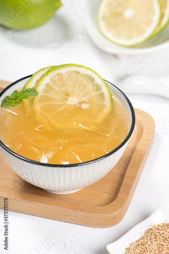 Taiwanese food - delicious cold drinking dessert Aiyu ice jelly in a white bowl and background with green lemon and mint topping, close up.