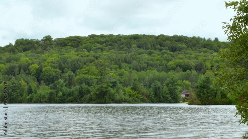 Timelapse - Clouds Stir Over Forested Hill and Choppy Lake Timelapse - Clouds Stir Over Forested Hill and Choppy Lake