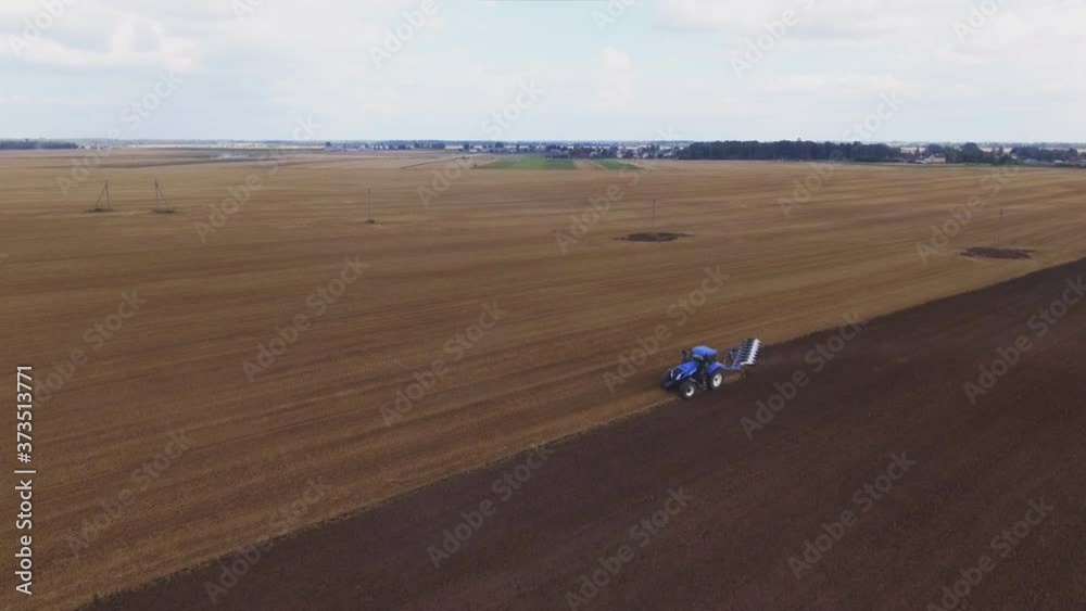 Blue Modern Plowing Tractor Working In The Field. Aerial Pedestal-Down Shot. Blue Modern Plowing Tractor Working In The Field. Aerial Pedestal-Down Shot.