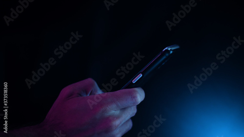 Hand using a smart phone in close up on a black background	
