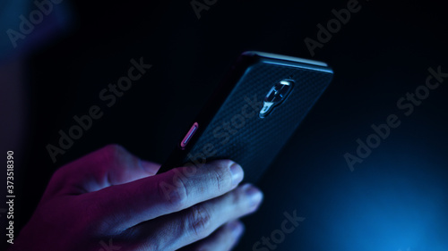 Hand using a smart phone in close up on a black background	

