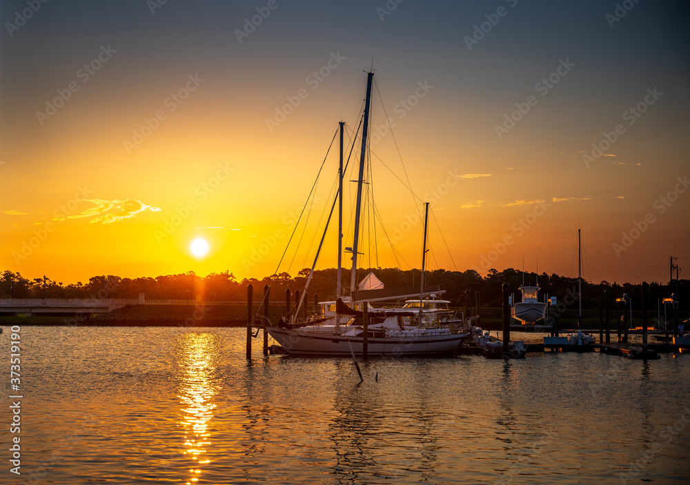 Sailboats at Sunrise at the marina on calm water in Beaufort North Carolina.