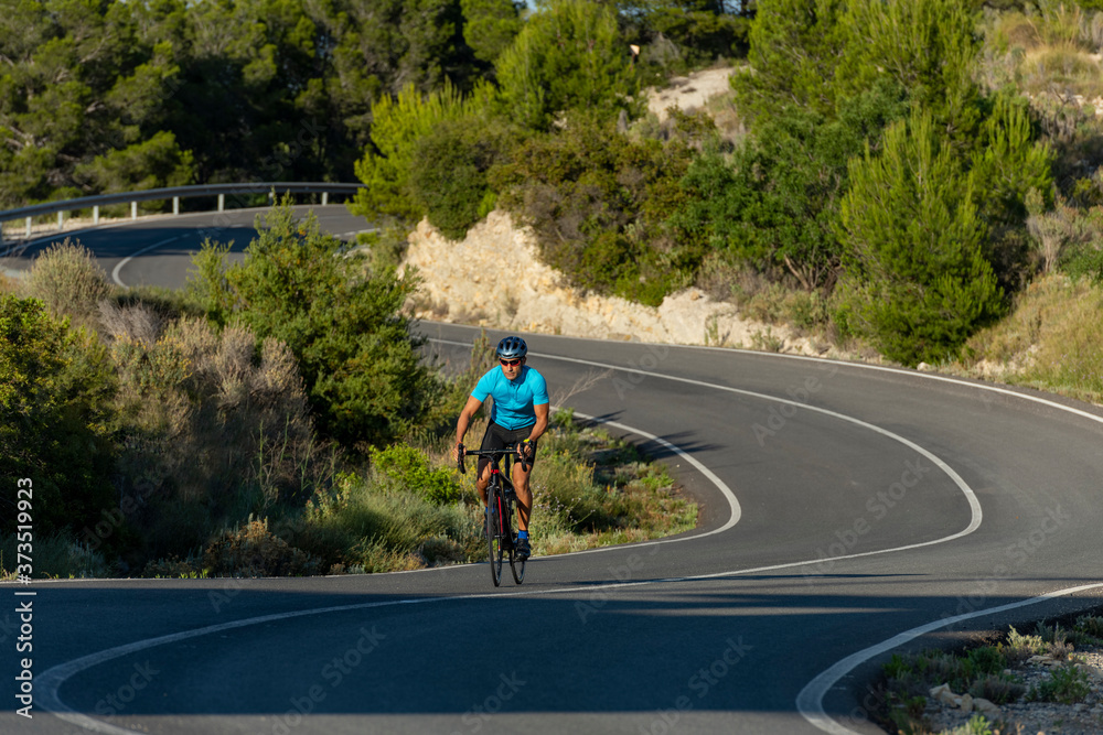 A man, standing up on his pedals, bikes uphill in Costa Blanca A man, standing up on his pedals, bikes uphill in Costa Blanca