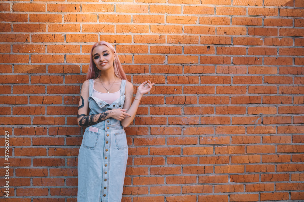 Half length portrait of trendy adolescent teenager dressed in casual jeans sundress smiling at camera near brick promotional background,happy Caucasian hipster girl posing at copy space publicity area Half length portrait of trendy adolescent teenager dressed in casual jeans sundress smiling at camera near brick promotional background,happy Caucasian hipster girl posing at copy space publicity area