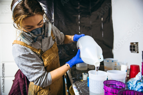 Female resin artist mixing and pouring with respirator mask photo