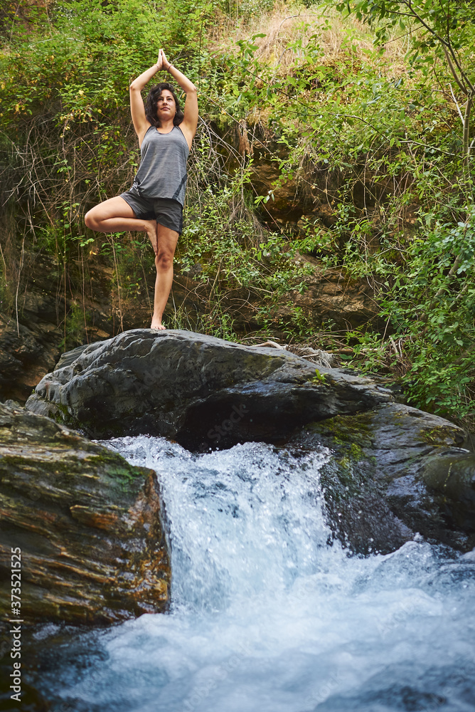 Young woman practicing yoga in a river. She's in the middle of nature. Young woman practicing yoga in a river. She's in the middle of nature.