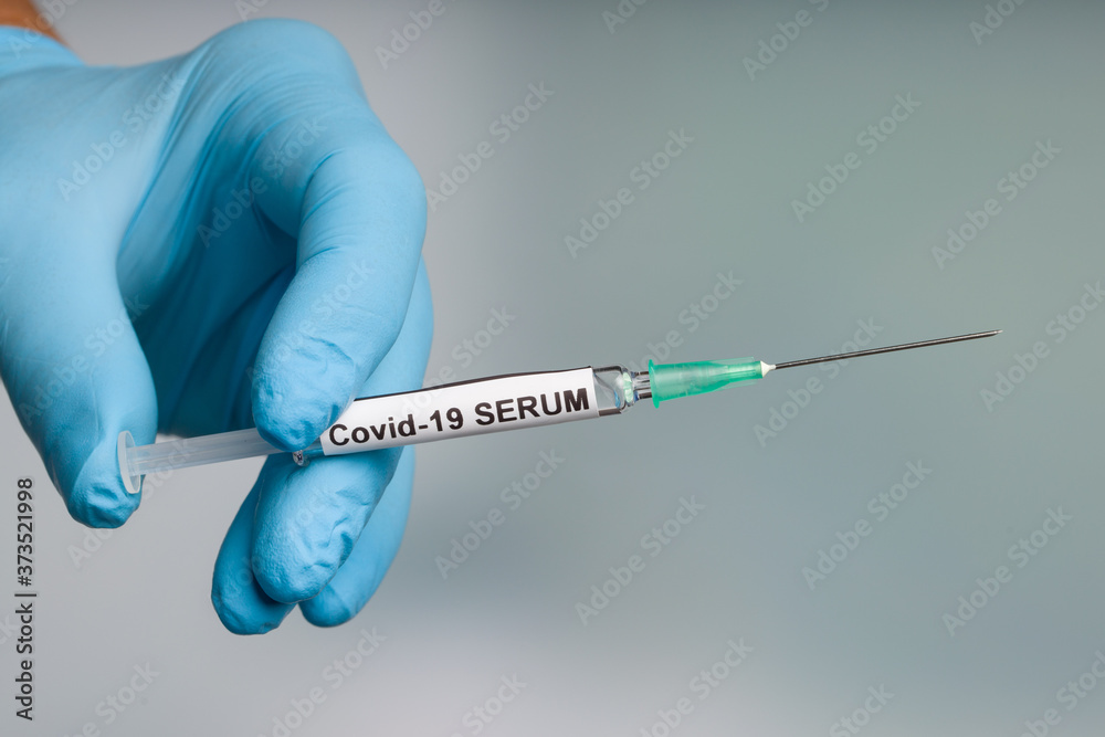Close up of doctor's hand in medical gloves with a syringe with Covid-19 serum ready for injection Close up of doctor's hand in medical gloves with a syringe with Covid-19 serum ready for injection