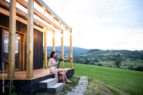 Foto Young couple with wine outdoors, weekend away in container house in countryside