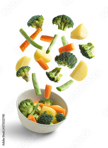 Boiled vegetables flying on white background. Creative concept