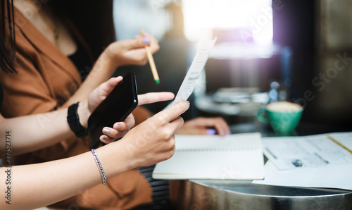 Close-up of hand young asian woman holding smart phone and paperwork working with her friend