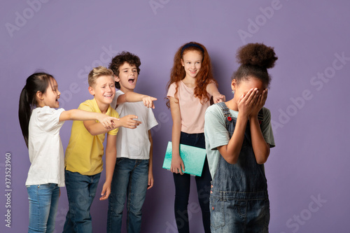 Φωτογραφία Group of schoolkids bullying their crying African American classmate over lilac