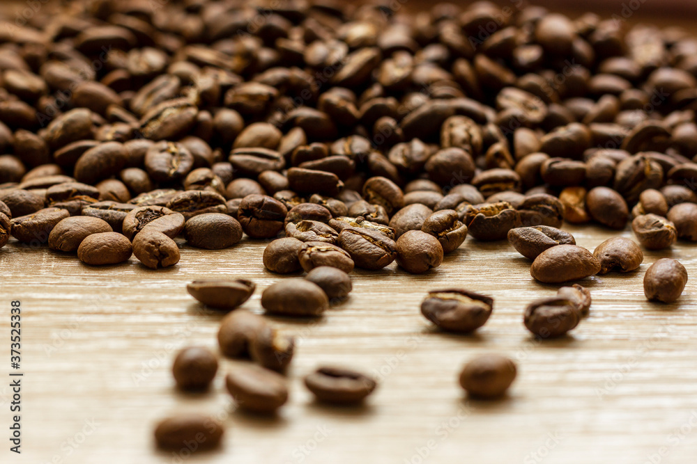 Roasted arabica coffee beans, in bulk on a wooden table. Roasted arabica coffee beans, in bulk on a wooden table.