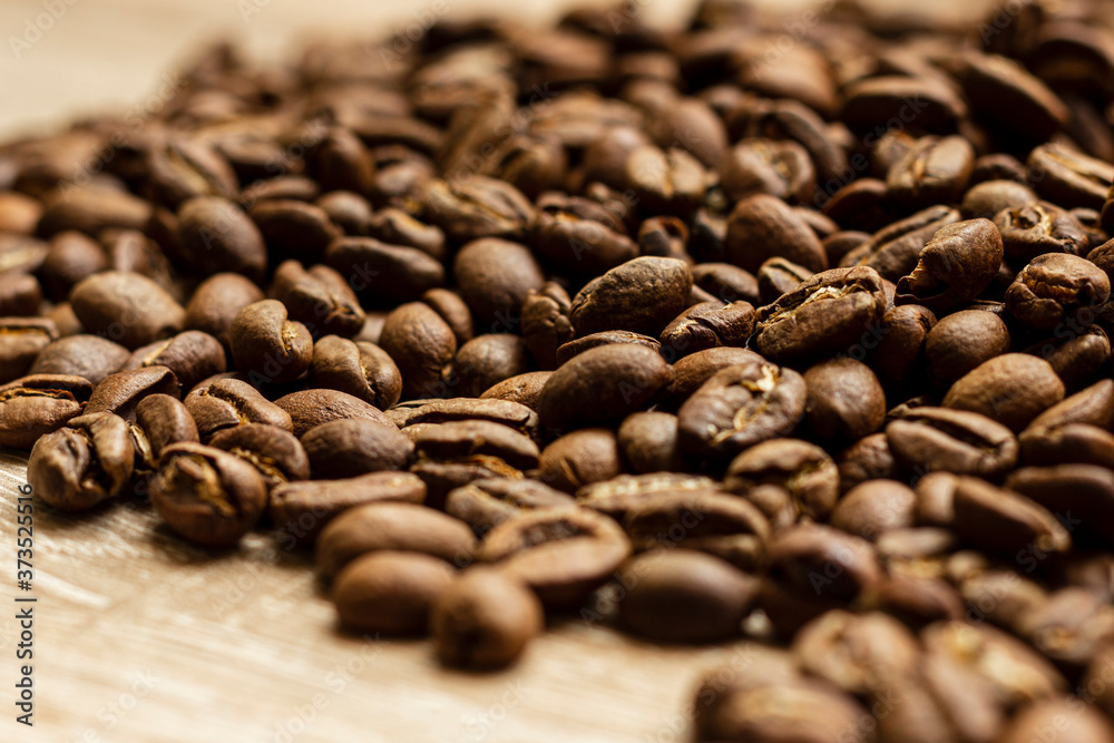 Roasted arabica coffee beans, in bulk on a wooden table. Roasted arabica coffee beans, in bulk on a wooden table.