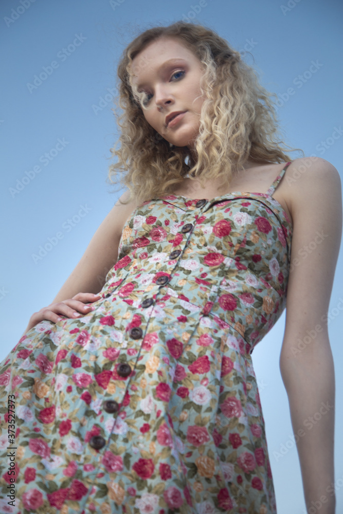 Φωτογραφία Low angle shot of a beautiful female with blonde curly hair wearing a cute dress