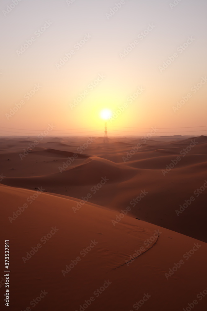 Portrait of beautiful desert sunrise with power transmission tower in the Arabian Desert, Riyadh, Saudi Arabia. Hope, new beginnings, brighter tomorrow and solar energy concept.
