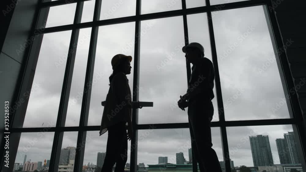 Silhouette of Architect and engineer construction workers shaking hands while working for teamwork and cooperation concept after finish an agreement in the office success collaboration concept.