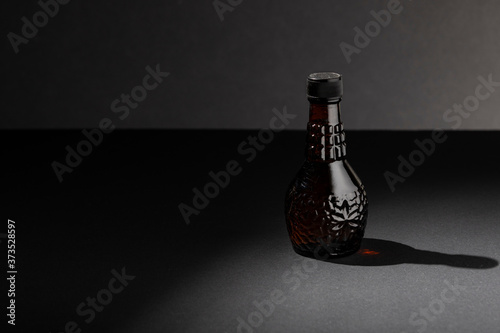 Photography in dark key. Still life of bottle of poison or perfume. Still life of dark glass bottle, in a low key composition, dark and with negative space to place design elements on the left. photo