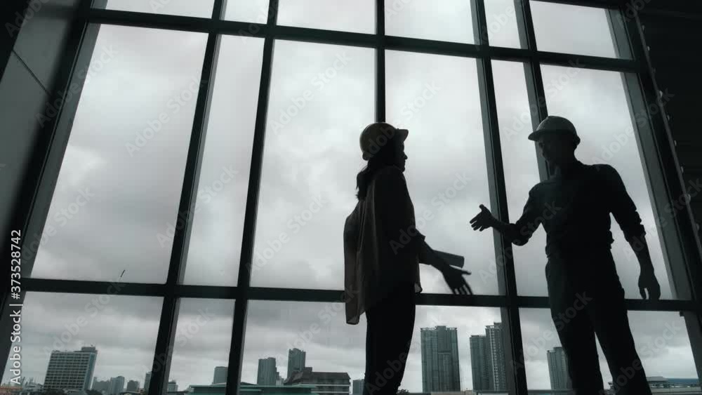 Silhouette of Architect and engineer construction workers shaking hands while working for teamwork and cooperation concept after finish an agreement in the office success collaboration concept. Silhouette of Architect and engineer construction workers shaking hands while working for teamwork and cooperation concept after finish an agreement in the office success collaboration concept.