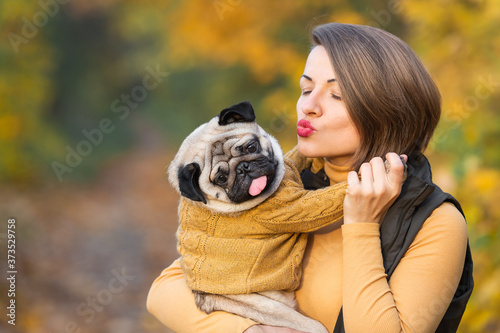 girl kisses a pug in the autumn in the park © Marina Varnava