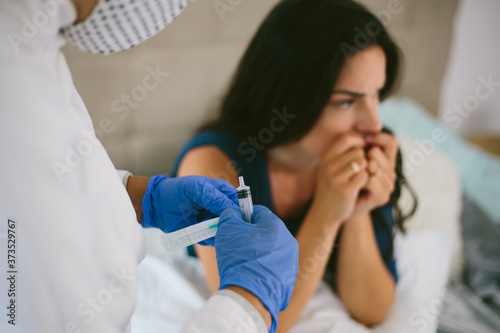 The female doctor in protective equipment a mask, gloves performs the vaccination procedure. Human vaccination process against coronavirus. Female scared getting an injection from a doctor.