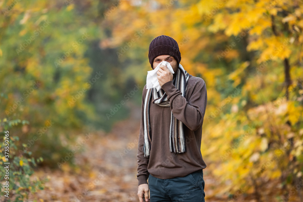 Sick man blows his nose on an autumn day Sick man blows his nose on an autumn day
