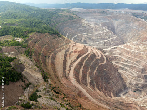Open pit ore mining.
Photo of a pit for mining ore from the air. A string of roads in the mountains dug by man.