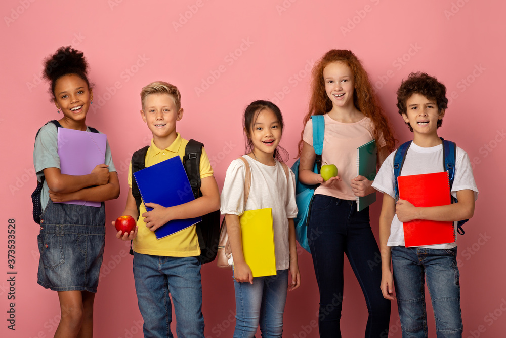 Getting ready for new school year. Diverse children with backpacks, notebooks and apple fruits on pink background Getting ready for new school year. Diverse children with backpacks, notebooks and apple fruits on pink background