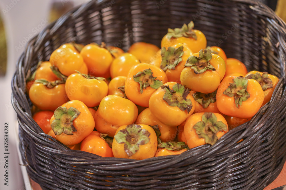 Lots of persimmon in basket at bazaar. agriculture farm full of organic vegetables. Pile of ripe persimmon in the store. (selective focus)