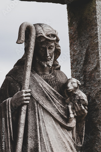 Dark contrast image of Jesus figure holding baby lamb and Shepard’s crook/staff photo