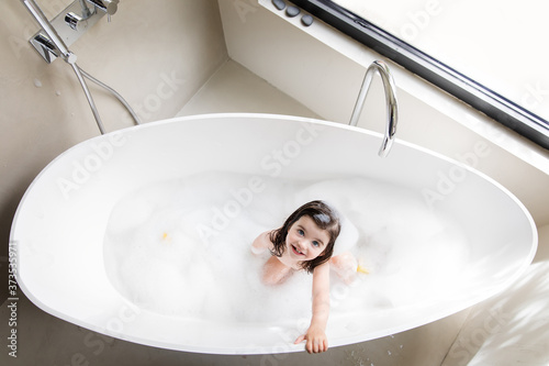 High angle portrait of toddler girl taking bath in bathtub at home