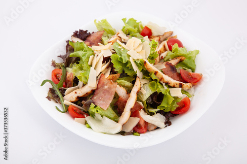 Fresh caesar salad with chicken fillet, cherry tomatoes on white plate.