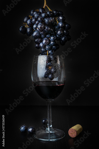 still life with glass of red wine and bunch of grapes. Black Background