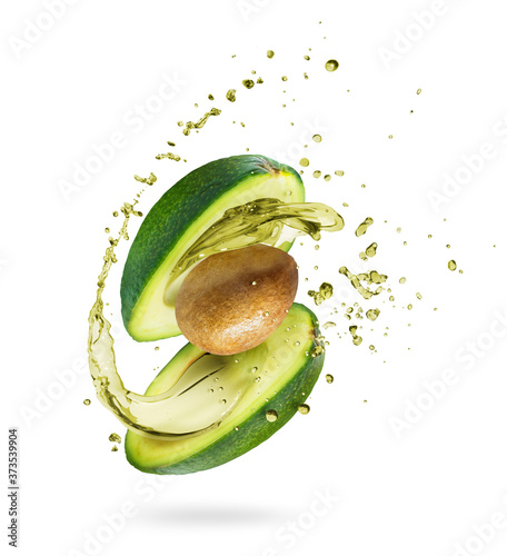 Sliced avocado with splashes of juice close-up, isolated on a green background photo