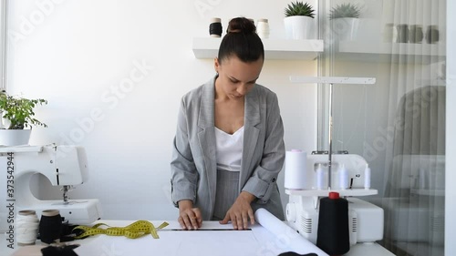 Young woman tailor is designing a new dress in her mini workshop.