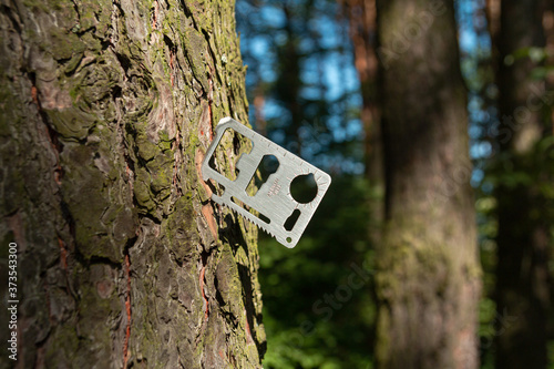 A multi-tool made from a single sheet of metal is stuck into the wood.