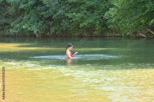 Girl on a natural river taps her hands in the water 