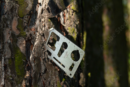 A multi-tool made from a single sheet of metal is stuck into the wood.