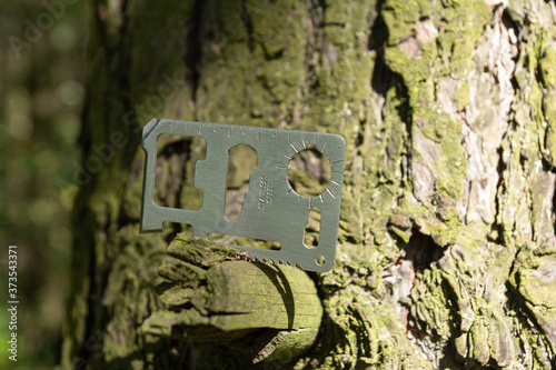A multi-tool made from a single sheet of metal is stuck into the wood.