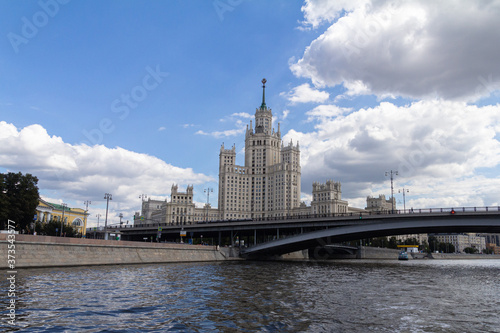 An old multi-storey building of white stone on the banks of the city river.