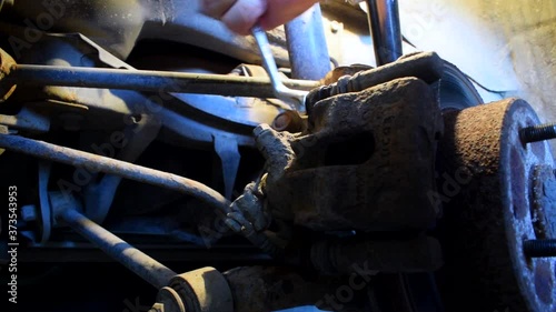 Unscrewing the bolt on a rusted brake caliper