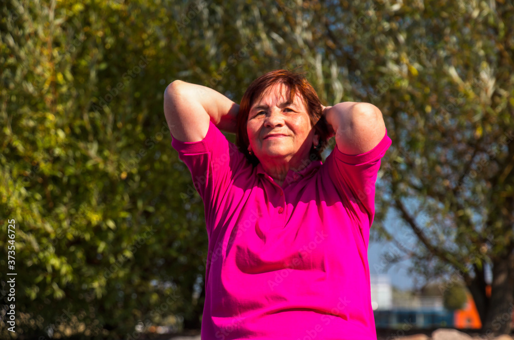 older woman doing outdoor exercise on a bright autumn day older woman doing outdoor exercise on a bright autumn day