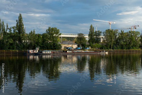reflection of boats in the water with cranes behind